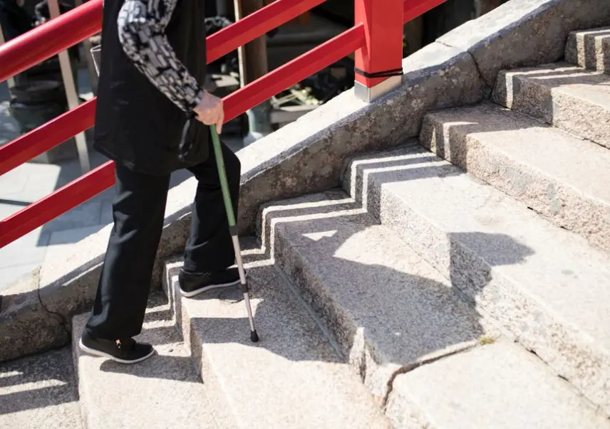 樓梯升降椅選購指南主視覺 長者持手杖走上戶外石階,呈現上下樓梯的行動需求