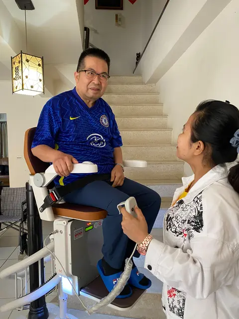 照顧者在先生身旁陪同操作樓梯升降椅